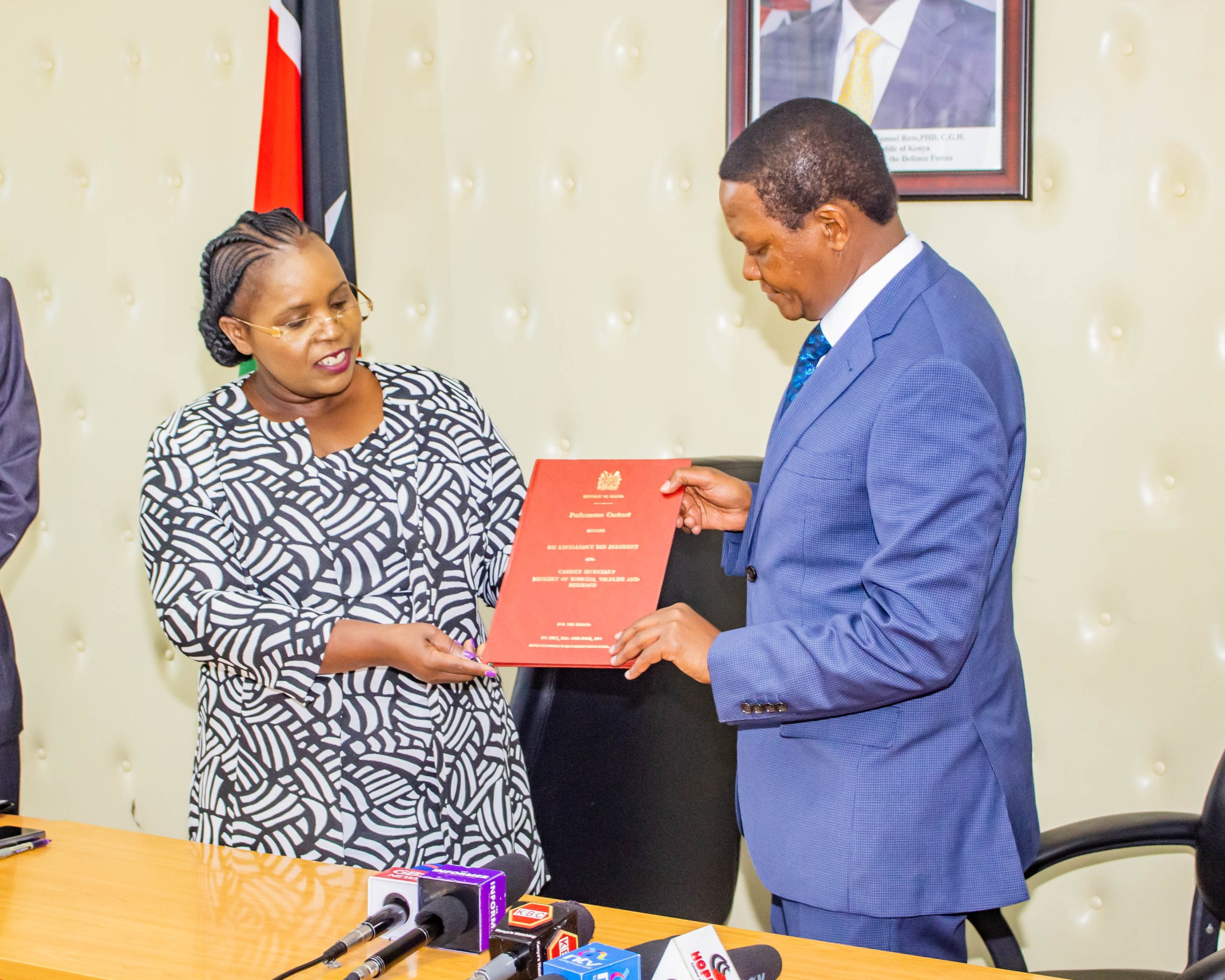 Outgoing Cabinet Secretary (CS) Hon. Peninah Malonza gives a handover report to incoming CS Dr. Alfred Mutua.