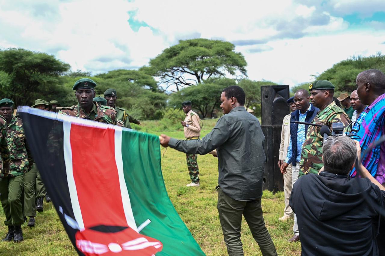 CS Mutua raising the Kenyan flag during the Utalii Fesh Tours function in Kajiado county